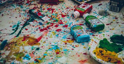 A messy artists table covered in multple paint splatters